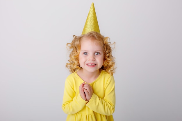 una bambina che festeggia il suo compleanno esprime un desiderio su uno sfondo bianco