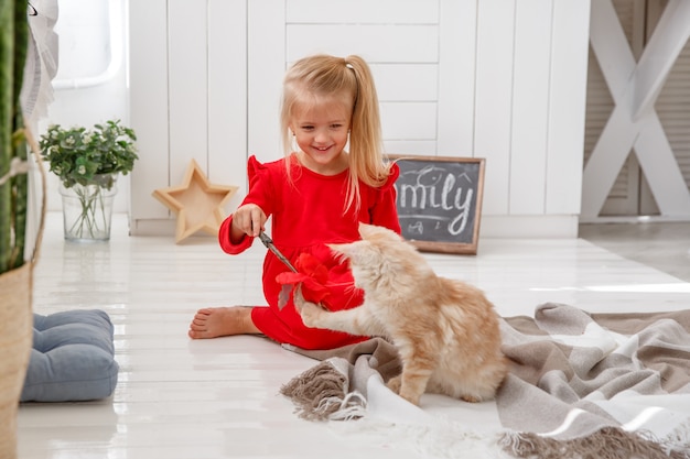 Una bambina che gioca con i gattini sul pavimento della casa. Il concetto di famiglia umana e animale domestico