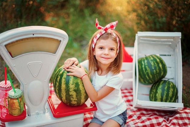 Una bambina che pesa un'anguria