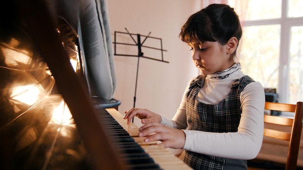 Una bambina che suona il pianoforte sulla bella lezione di musica alla luce del sole