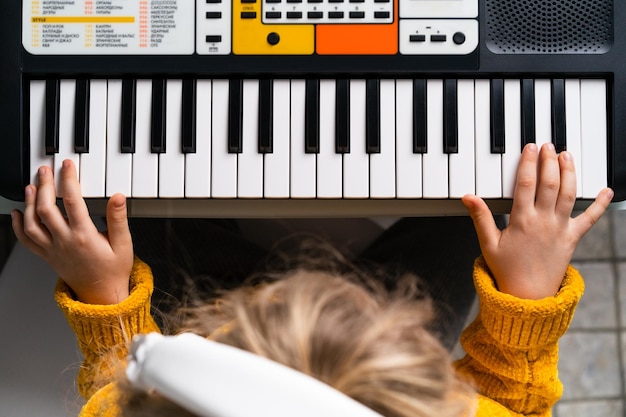 Una bambina che suona il sintetizzatore il concetto di insegnare ai bambini la musica vista dall'alto