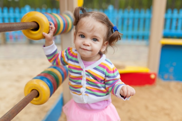 Una bambina con due code che giocano nella sandbox nel parco giochi