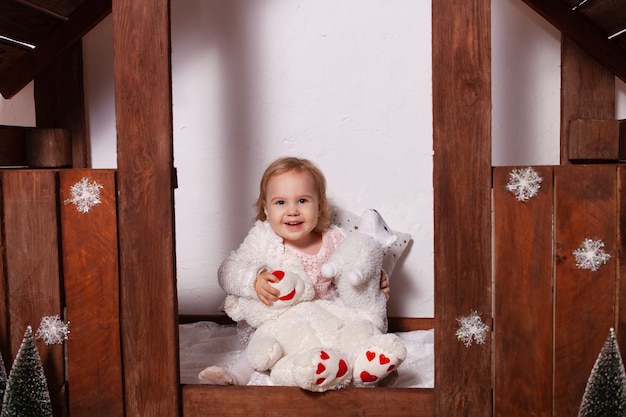 Una bambina con i giocattoli in una casa di legno. Decorazioni natalizie.