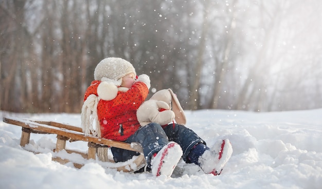 una bambina con un cappello soffice cammina in una giornata invernale innevata