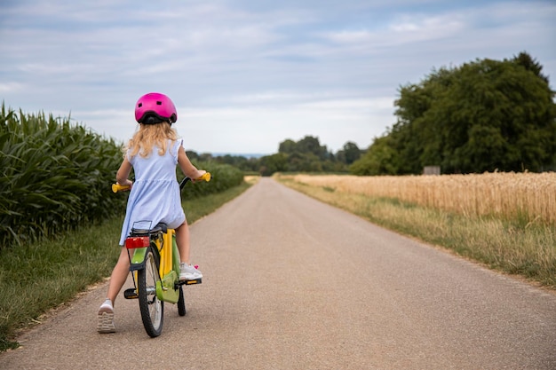 Una bambina con un casco va in bicicletta in un campo