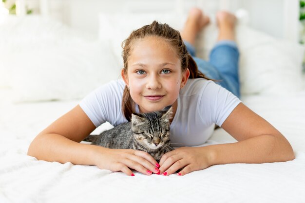 Una bambina con un gatto è sdraiata sul letto