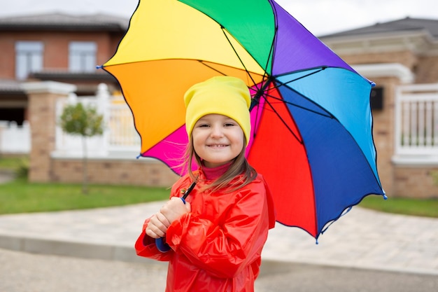 Una bambina con un ombrello colorato e un impermeabile impermeabile in una giornata autunnale