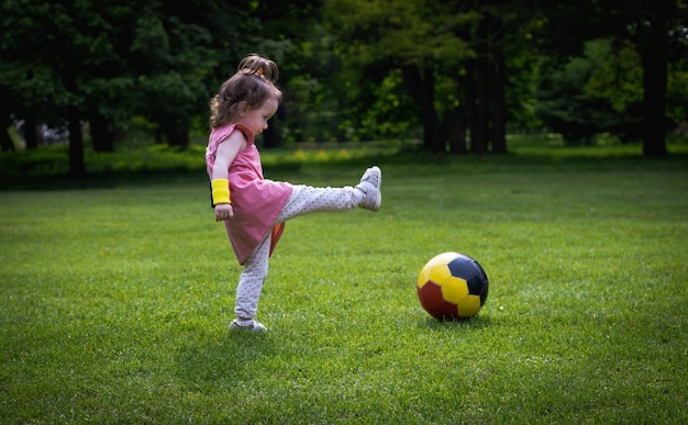 Una bambina con un pallone da calcio sul prato