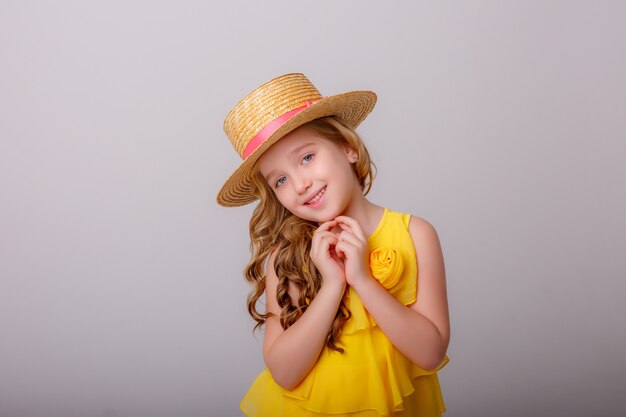 una bambina con un vestito giallo e un cappello di paglia