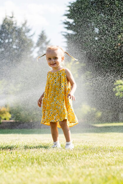 Una bambina con un vestito giallo spruzza uno spruzzatore.