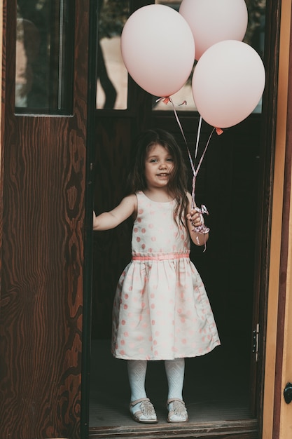 Una bambina con un vestito rosa esce dal tram con le palle. Foto di alta qualità