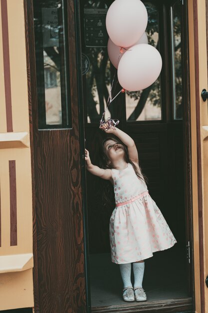 Una bambina con un vestito rosa esce dal tram con le palle. Foto di alta qualità