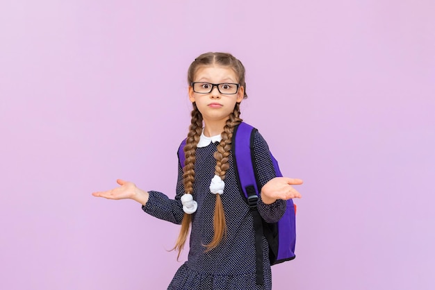 Una bambina con una borsa da scuola, un'uniforme scolastica e lunghe trecce, sta andando a scuola l'istruzione primaria a scuola e la preparazione per gli esami