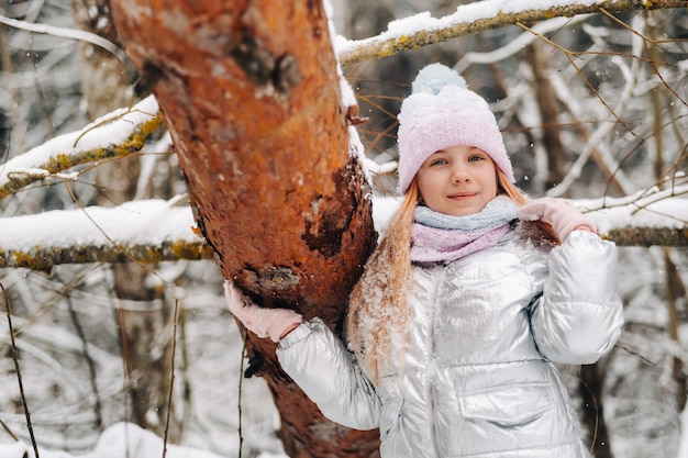 Una bambina con una giacca argentata d'inverno esce fuori d'inverno.