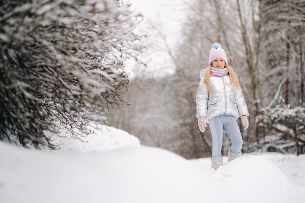 Una bambina con una giacca argentata d'inverno esce fuori d'inverno