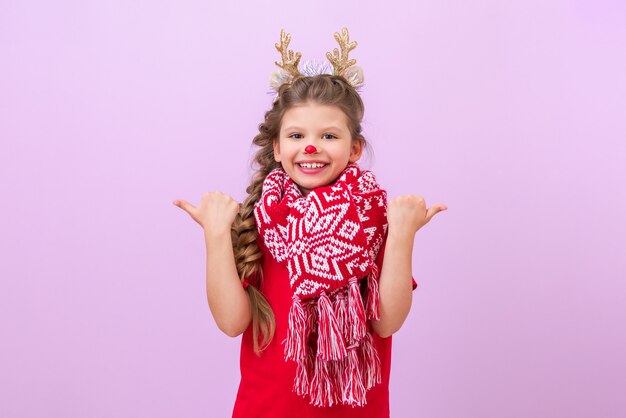 Una bambina con una maschera da cervo di Capodanno punta le dita in direzioni diverse.