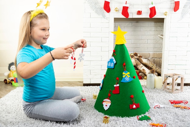 Una bambina decora un albero di feltro