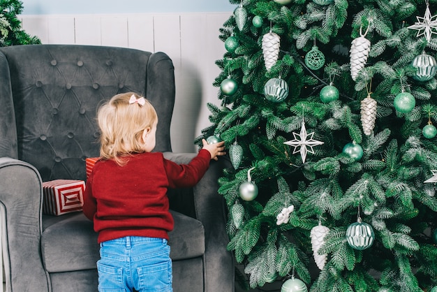 Una bambina decora un albero di Natale