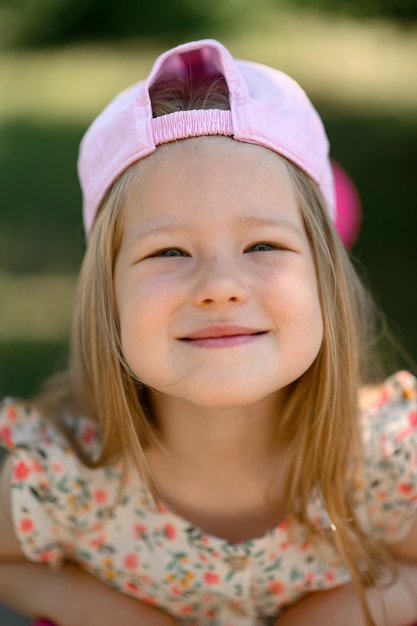 Una bambina di 3 anni con un berretto rosa guida uno scooter Orario estivo