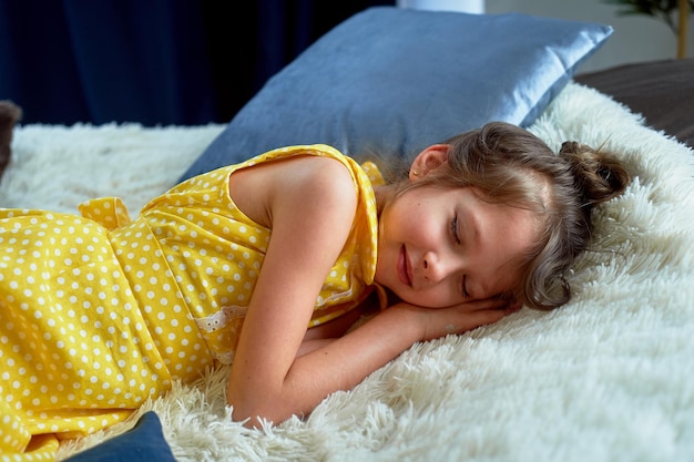 Una bambina di 6 anni con un vestito giallo mi sono addormentata con i miei vestiti su Stanchezza dal gioco e dall'attività cerebrale Ero affamata