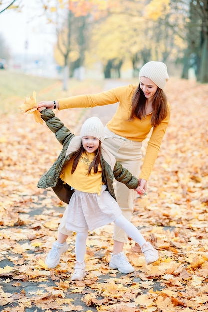 Una bambina di cinque anni, aprendo la bocca con ammirazione e gioia, gioca con sua madre nel parco autunnale. mamma e figlia si divertono all'aperto in autunno