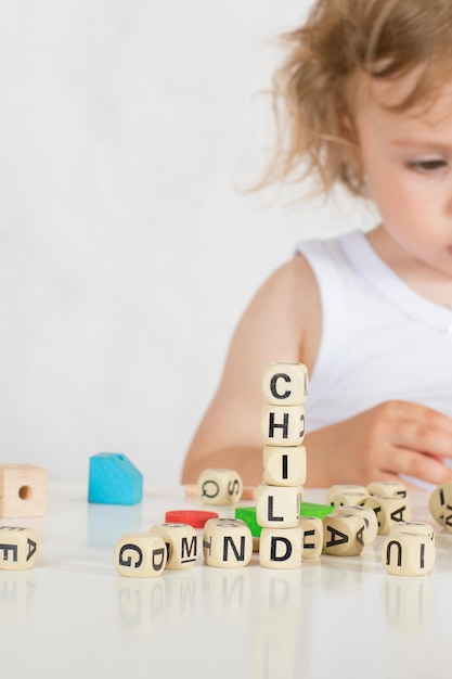 Una bambina di due anni compone parole da lettere. Avvicinamento