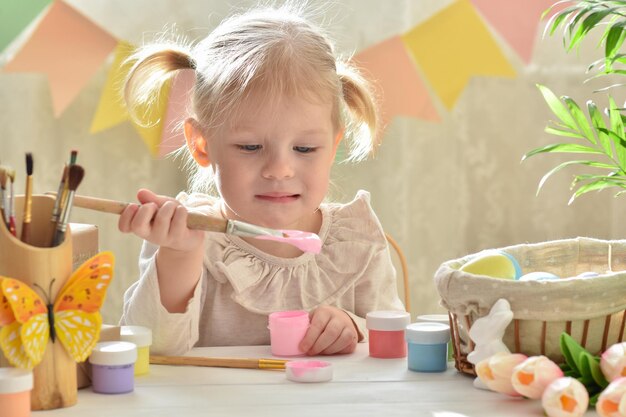 Una bambina di due anni dipinge le uova di Pasqua Buona Pasqua Fai da te