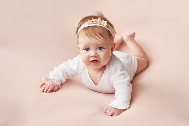Una bambina di quattro mesi giace su un muro rosa chiaro