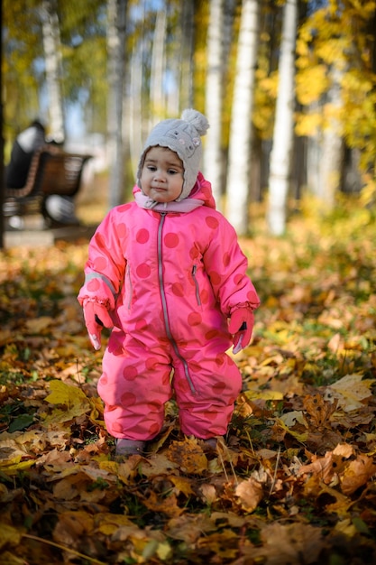 Una bambina di un anno con una tuta rossa durante una passeggiata in autunno