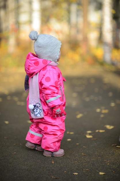 Una bambina di un anno con una tuta rossa durante una passeggiata in autunno