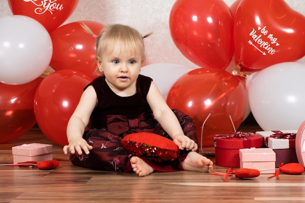 Una bambina di un anno gioca con il cuscino del cuore il giorno di San Valentino