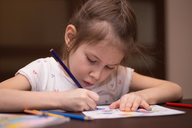 Una bambina disegna con le matite colorate