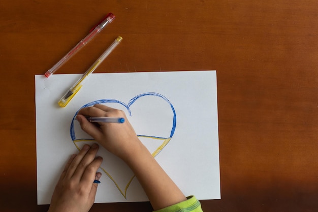 Una bambina disegna un cuore. Vista dall'alto. Copia spazio per il testo
