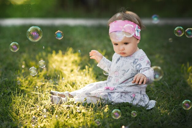 Una bambina è seduta su un prato verde e ammira le bolle di sapone 3431