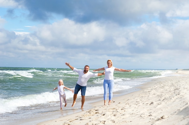 Una bambina ei suoi genitori camminano sulla spiaggia del Mar Baltico in Lituania.