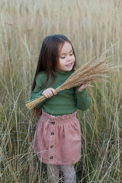 Una bambina felice che cammina sul grano dorato, godendosi la vita nel campo. Il concetto di libertà. Bambina carina nel campo autunnale