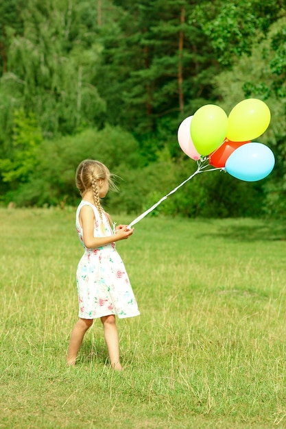 Una bambina felice con palloncini sulla natura