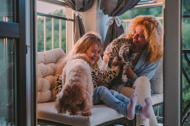 Una bambina felice, un bambino con un sorriso, gioca in una vernada primaverile estiva a casa con mamma e un cane