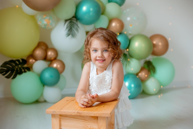 Una bambina festeggia il suo compleanno sullo sfondo di palloncini verdi