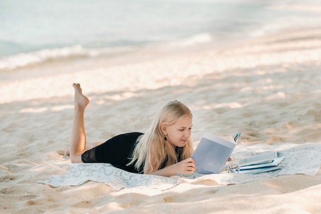 Una bambina giace e si gode la spiaggia tropicale di Le Morne a Mauritius. Una ragazza legge un libro su una spiaggia a Mauritius.