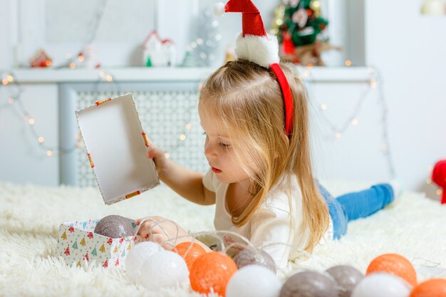 Una bambina giace su una coperta e tiene un regalo.