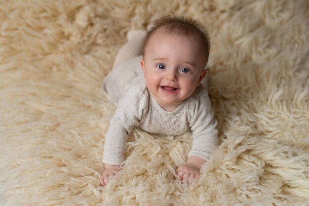 Una bambina giace su uno sfondo di pelliccia beige e sorride Le emozioni dei bambini