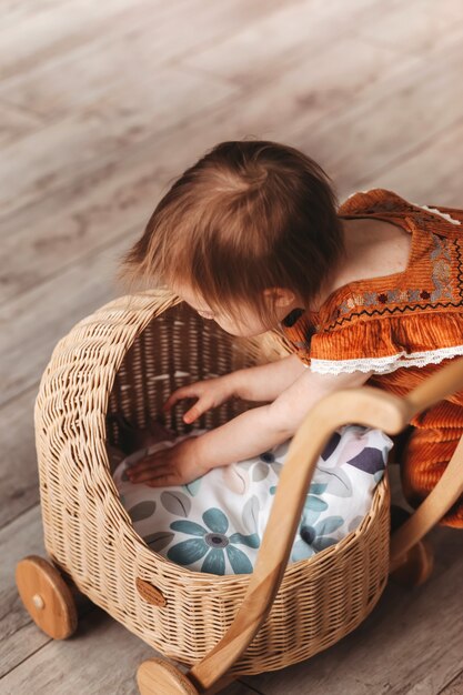 Una bambina gioca con le bambole e una carrozzina. La stanza dei bambini. Infanzia felice