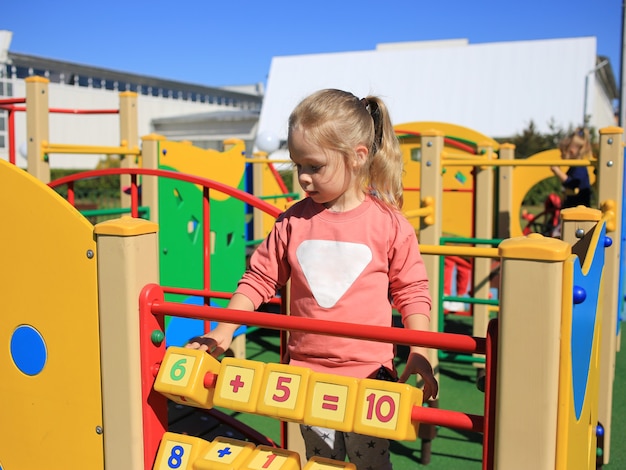 Una bambina, giocando a cubetti con figure in un parco giochi per bambini.