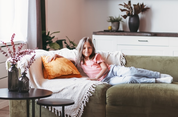 Una bambina graziosa che riposa sul divano in una stanza luminosa.