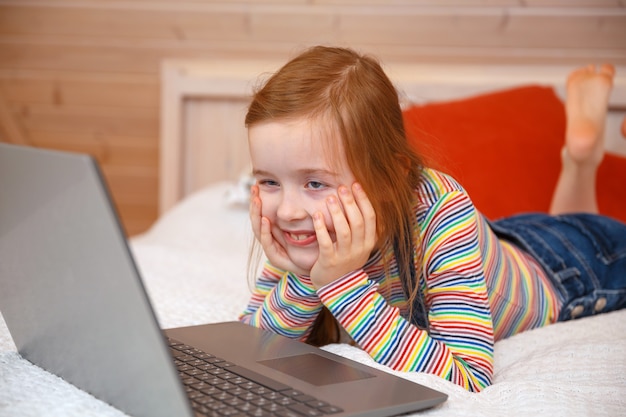 Una bambina guarda il computer con emozioni diverse. La ragazza gioca su un computer