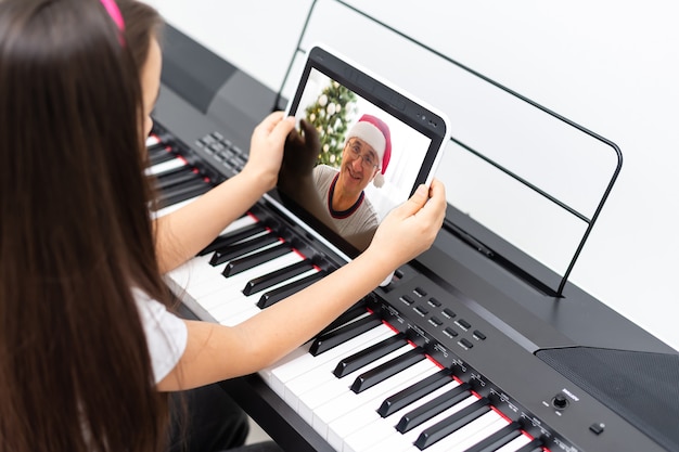 Una bambina impara a suonare il pianoforte dalle video lezioni. Didattica a distanza online durante il covid-19