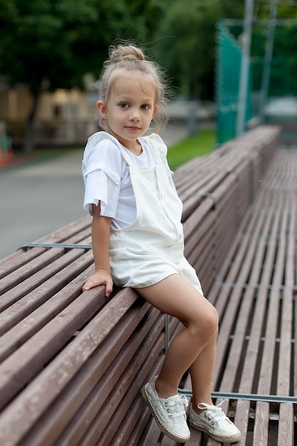 Una bambina in abiti leggeri cammina nel parco. Cammina all'aperto. Giornata estiva.