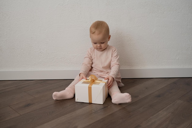 Una bambina in abiti rosa con un regalo su uno sfondo bianco