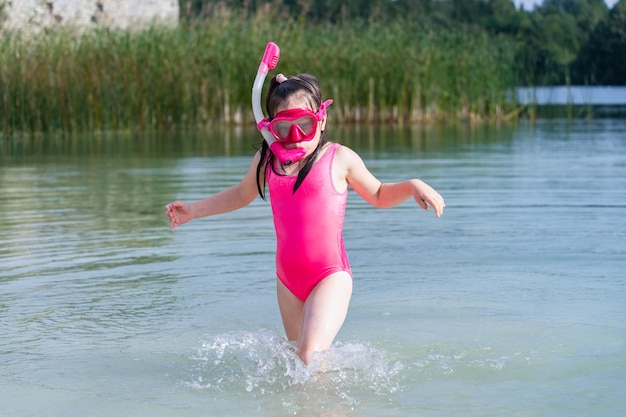 Una bambina in costume da bagno rosa con maschera e boccaglio fa snorkeling in estate nella cava di Rummu. Foto di alta qualità